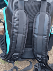 photo of the back of a mint green coloured waterproof bag, showing the padded area and the carrying straps