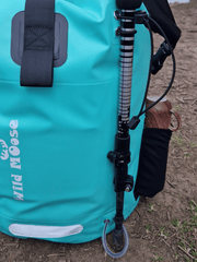 close up of the loop detail on a mint green coloured waterproof bag. with a walking pole help onto the backpack by the loops