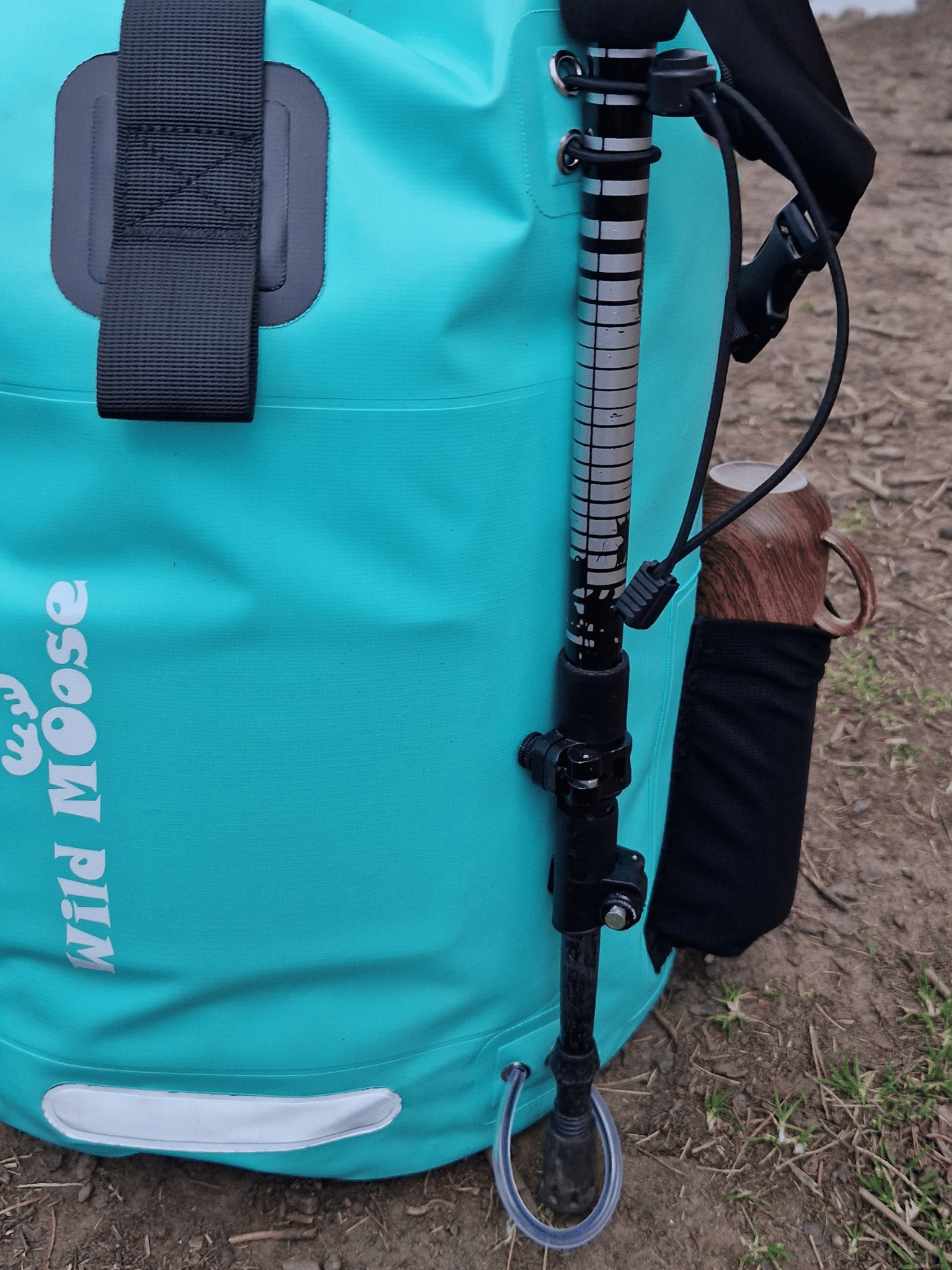close up of the loop detail on a mint green coloured waterproof bag. with a walking pole help onto the backpack by the loops