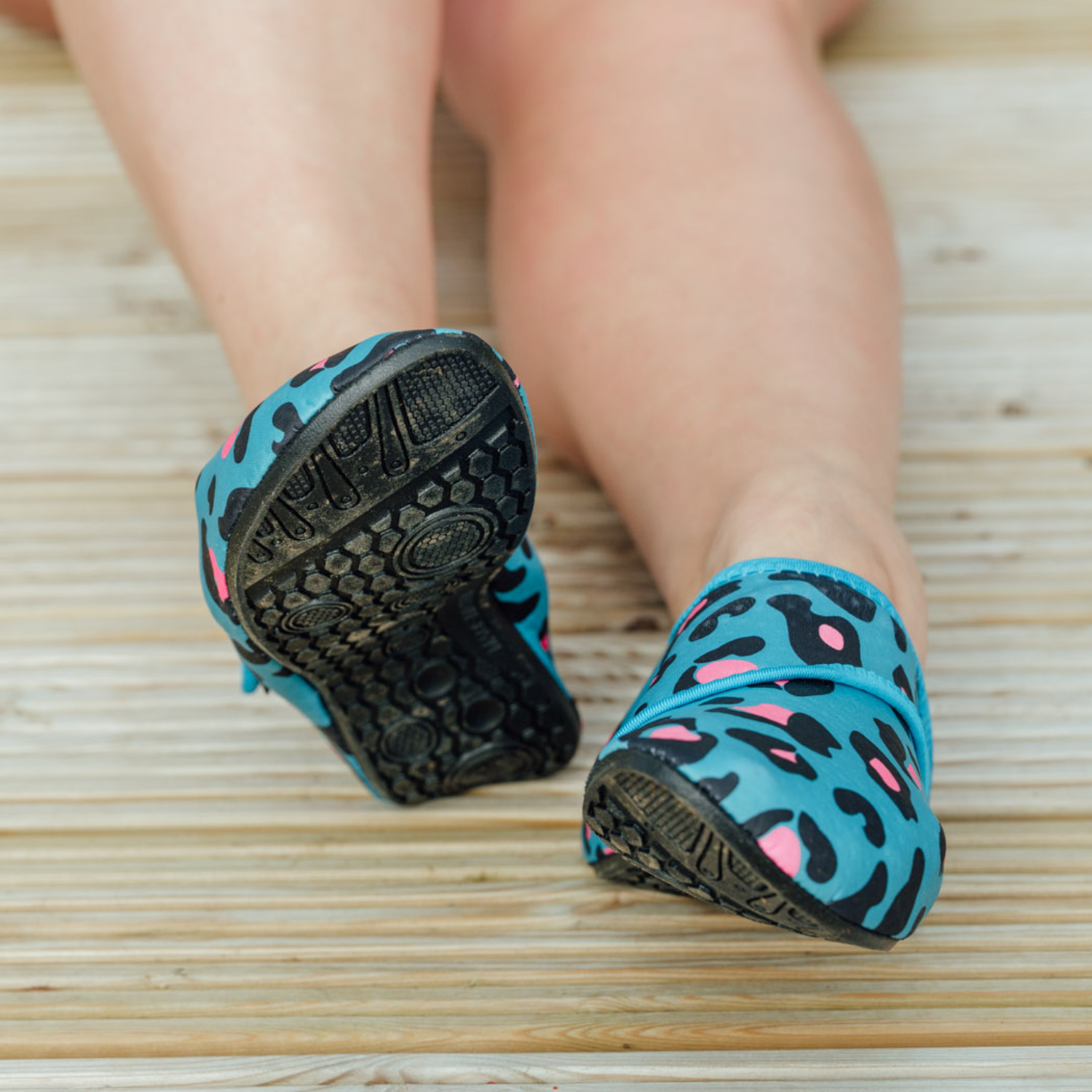 Blue leopard print neoprene beach shoes on a wooden floor