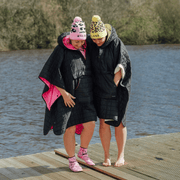 Image of 2 women wearing weatherproof black robes with large front pocket, side popper fastening, hood and fleece lining