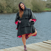Image of woman wearing weatherproof black robe with large front pocket, side popper fastening, hood and pink fleece lining