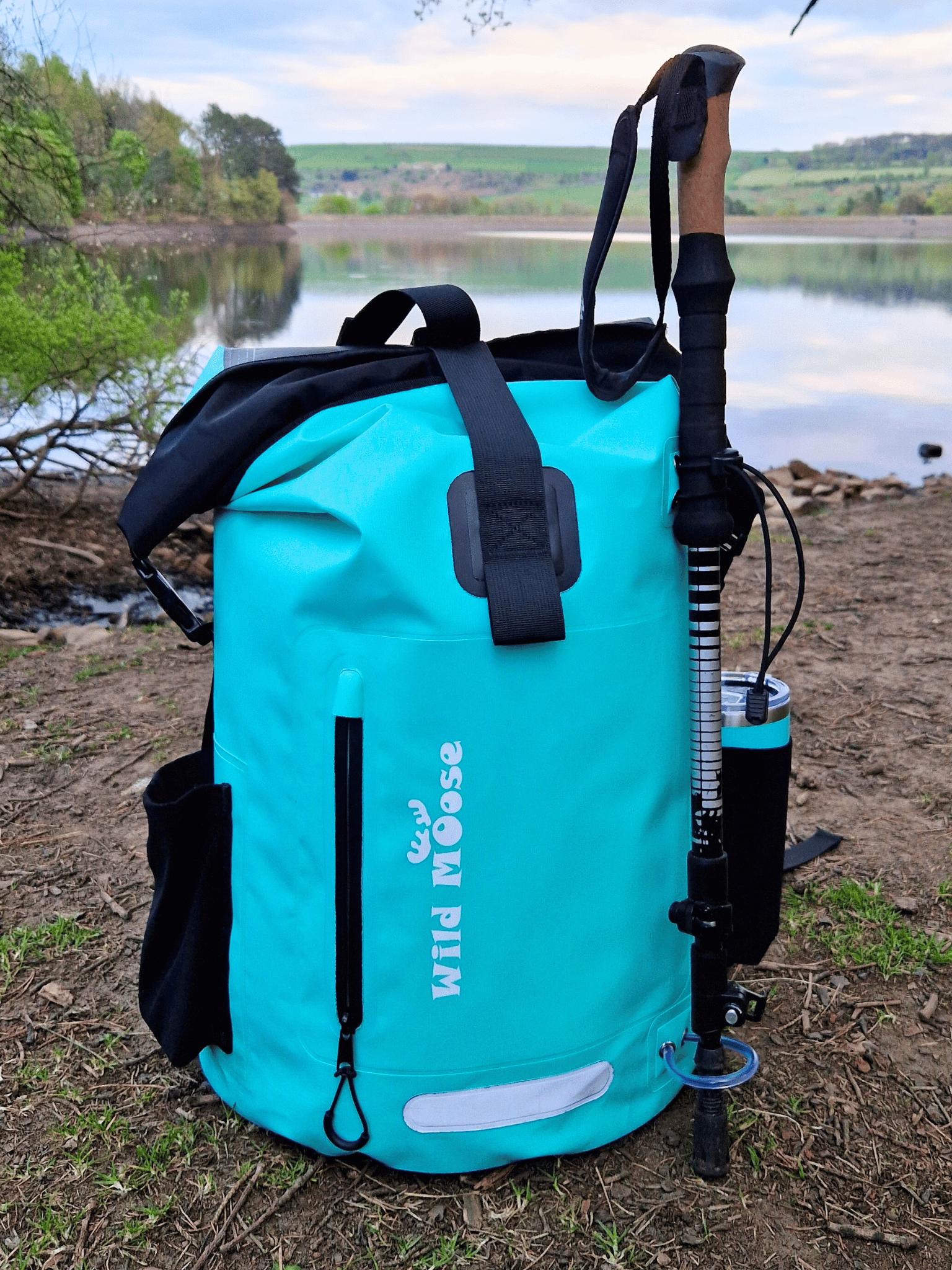 mint green coloured waterproof bag in front of a lake