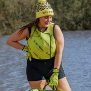 Person wearing a yellow and black outfit with whale print pattern stood lakeside outdoors.