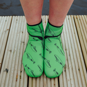 Green neoprene socks with whale pattern worn on a wooden dock.