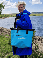 lady carrying bright blue tote bag, wearing an electric blue robe and stood next to a reservoir