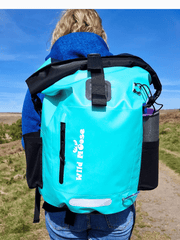 mint green coloured waterproof bag on a lady's bag. She is wearing and blue top and the sky is blue too